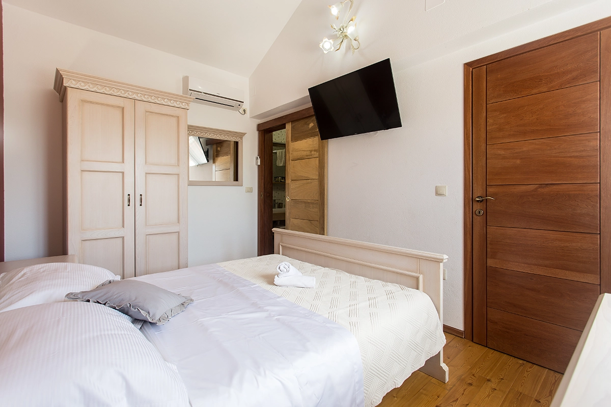 Room with an en-suite bathroom, air conditioning, television, double bed, and wardrobe.